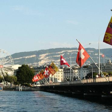 A body of water with a bridge and a ferris wheel in the background
